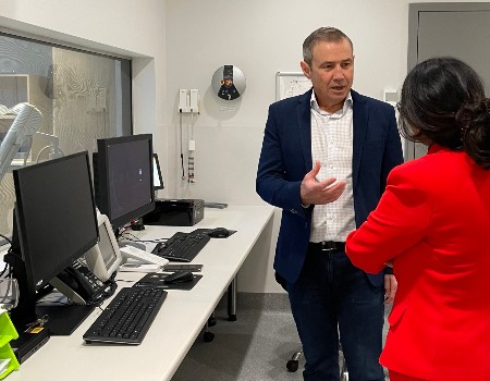 Health Minister talks to woman in front of MRI monitors 