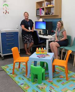 One health professional standing, the other sitting, both smiling.