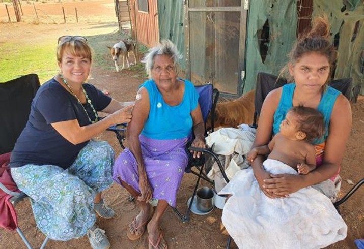 Doctor with vaccinated elderly community member, mother and child 