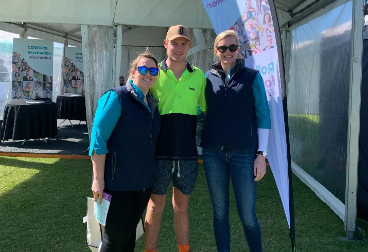 Three people stand outside tent