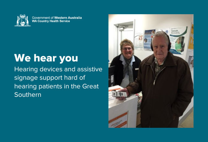 Volunteer wearing hearing device standing next to front desk administrator 