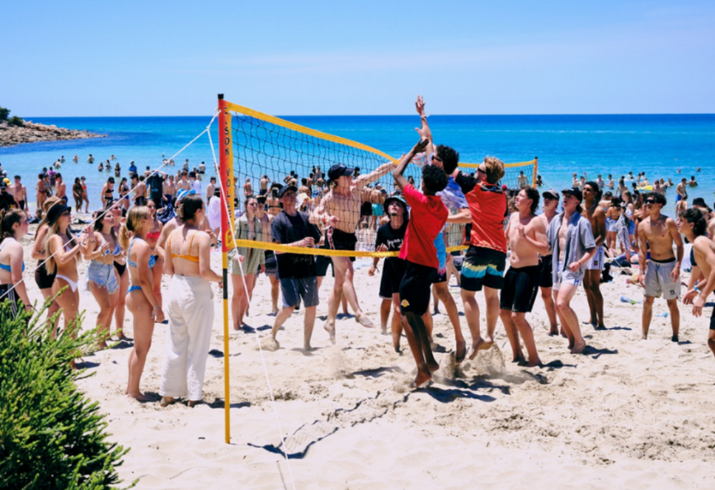A group of teenagers play beach volleyball