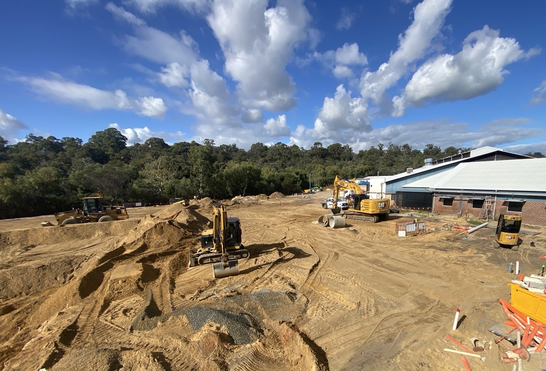 A large construction site with machinery and a large sand pad ready for concrete slabs