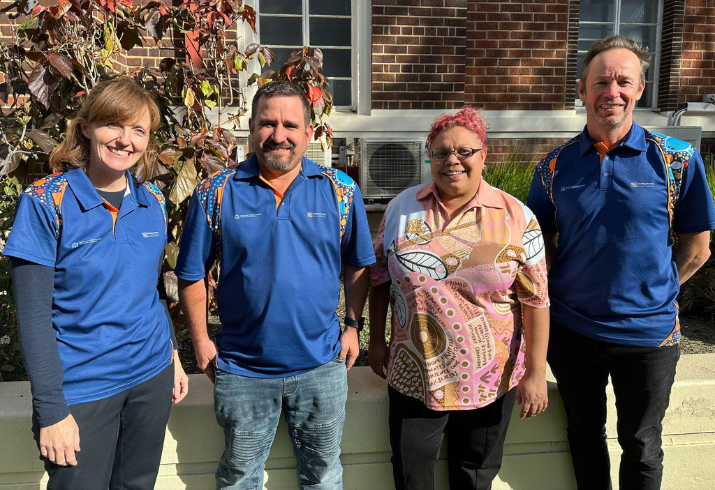 Four brightly dressed members of the Country PatHS team stand outside a building smiling