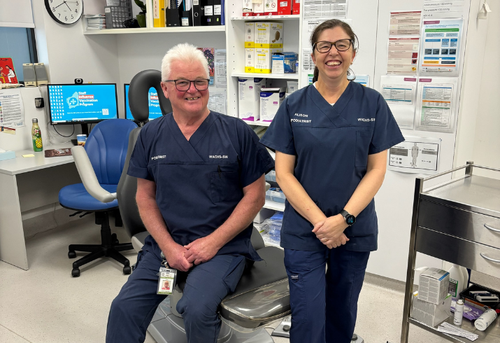 Two clinicians in scrubs in an office environment 
