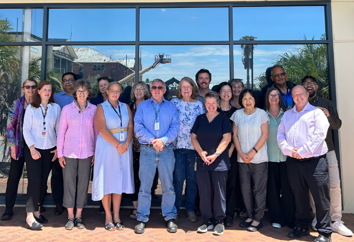 Group of staff standing in front of window.
