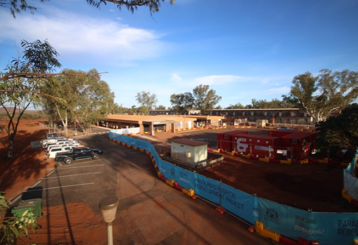 A busy construction site sits next to a regional hospital fenced off from the car park