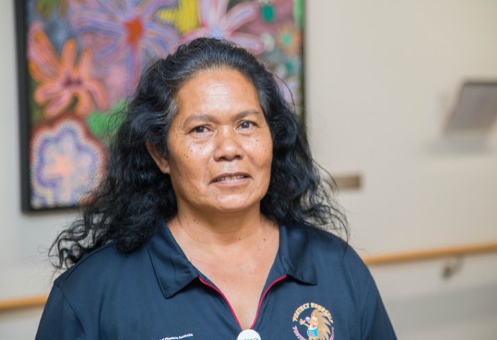 Woman standing in corridor smiling at camera.