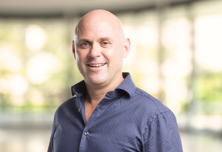 Headshot of man in navy blue button up shirt.