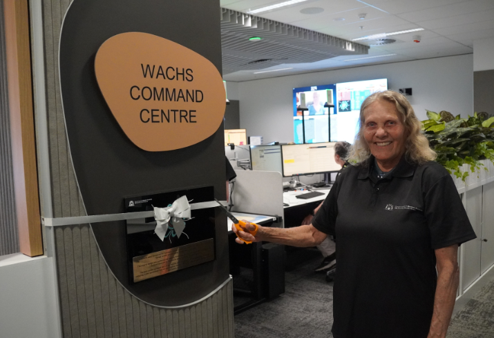 Violet Evans standing in an office next to a pull up banner with the words 'WACHS Command Centre'. 