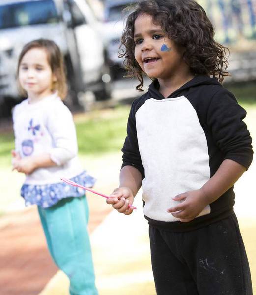 Smiling young boy in foreground holds a straw, young girl in background smiling