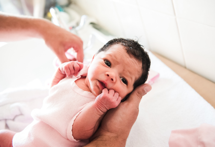 A parent cradles a newborn Aboriginal child