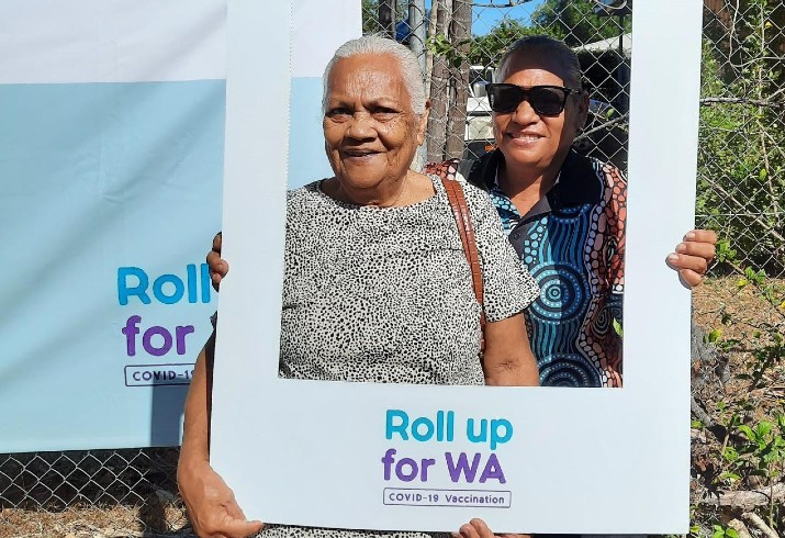 Two women pose with Rollup4WA banner after receiving the COVID-19 vaccination 