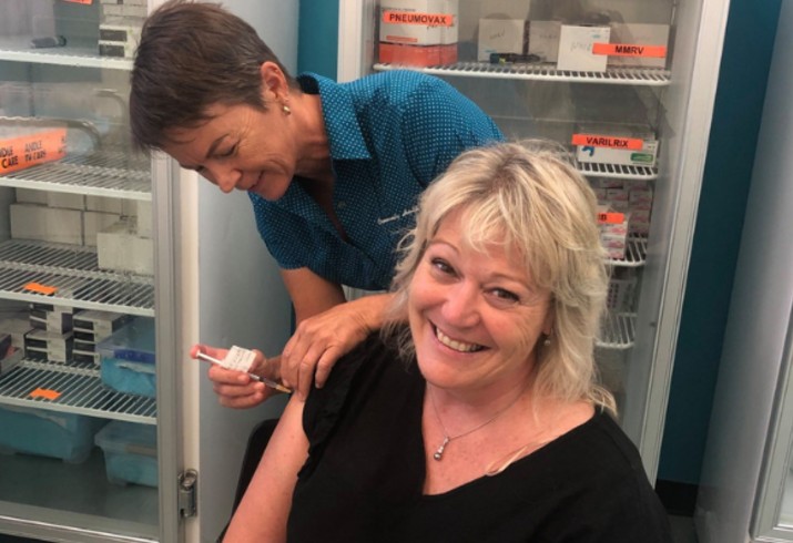 Women smiles as she receives COVID-19 vaccination by clinician