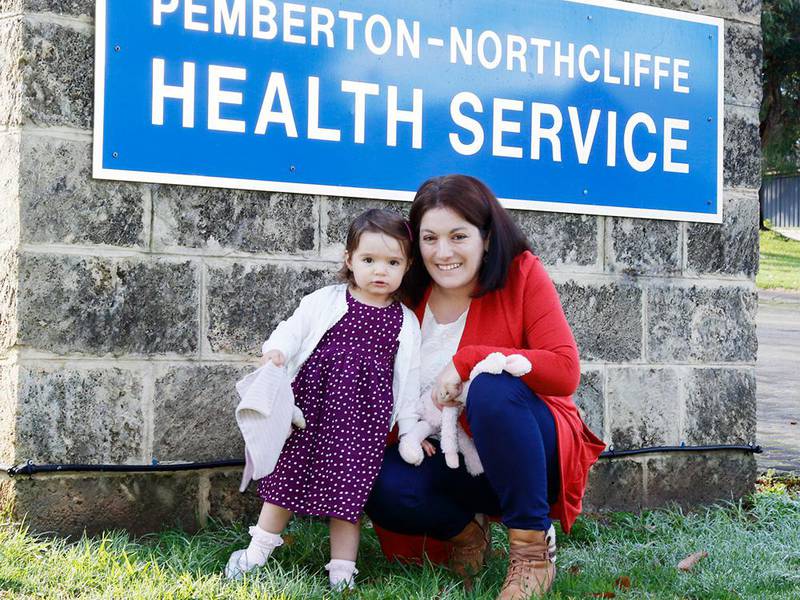 Ava Fuge and mum Marion in Pemberton Health Service’s emergency room with two of the clinicians who helped save her, nurse Jess Byers and Emergency Telehealth Service doctor Mlungisi Mahlangu (on screen). Credit: Robert Baker, Pemberton.