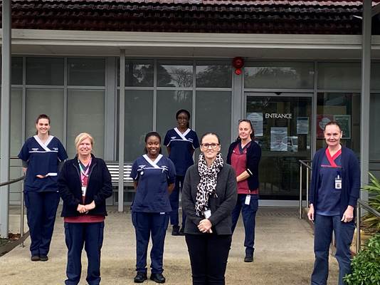 Seven WACHS staff members stand outside the entrance to Harvey Health Service